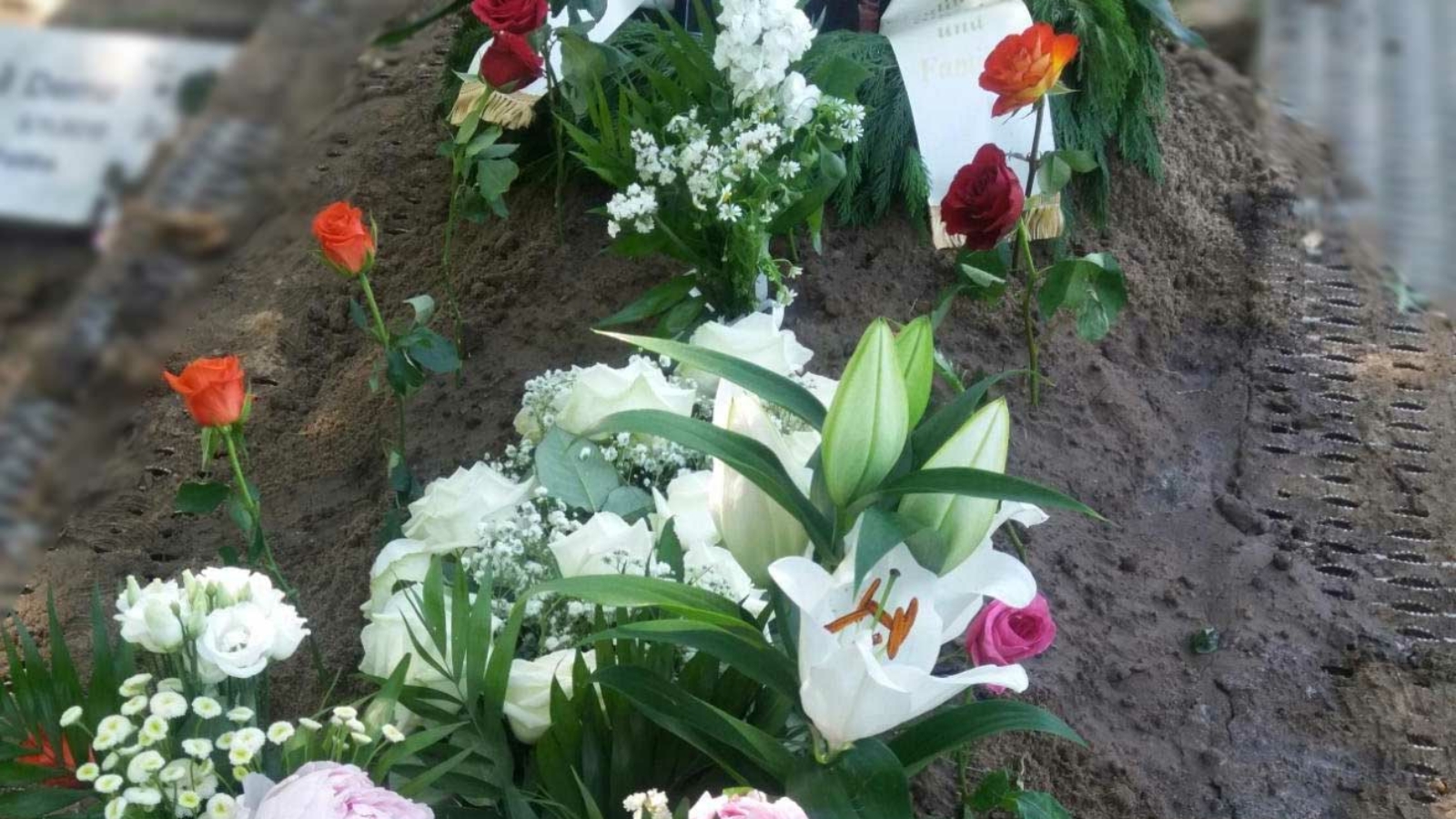 Arslans Grab mit vielen Blumen und einem Foto von ihm
